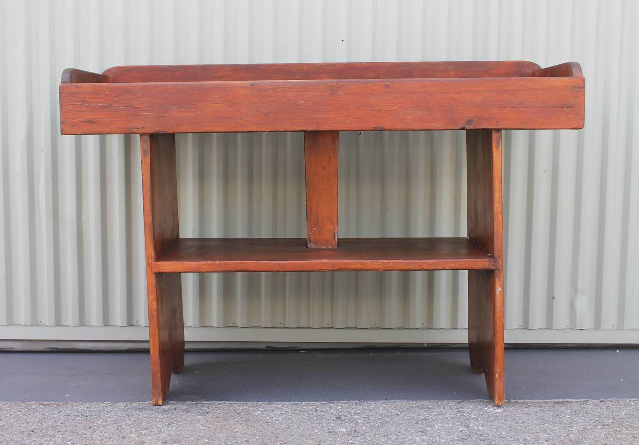 Early 19th century dry sink in pine from Pennsylvania in original worn old surface. This dry sink or bucket bench sink has a great till with drain lines throughout the top inset. The surface has a slight red painted cast but more worn natural