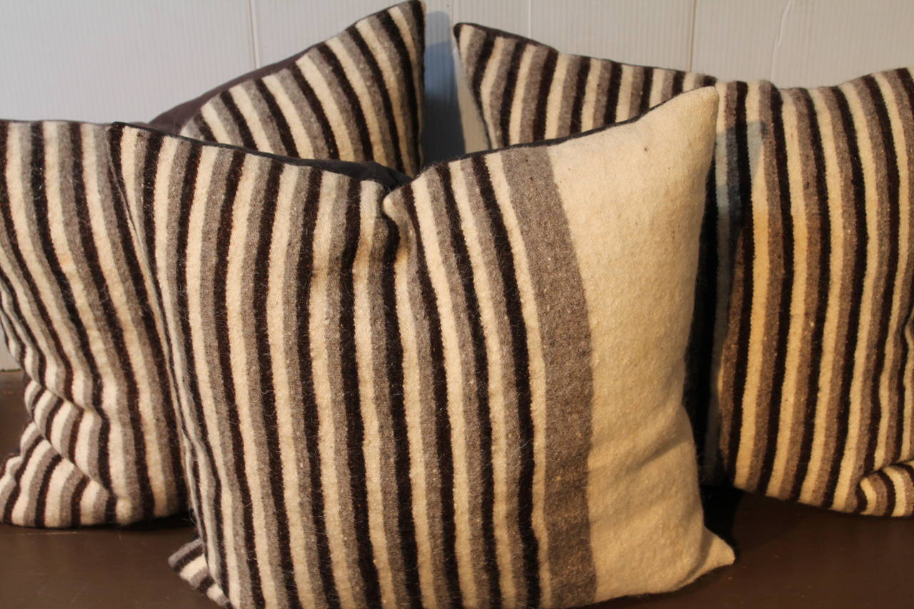Set of three handwoven saddle blanket pillows. The colors are brown and cream. The backing is in a brown cotton linen. Inserts down and feather fill.