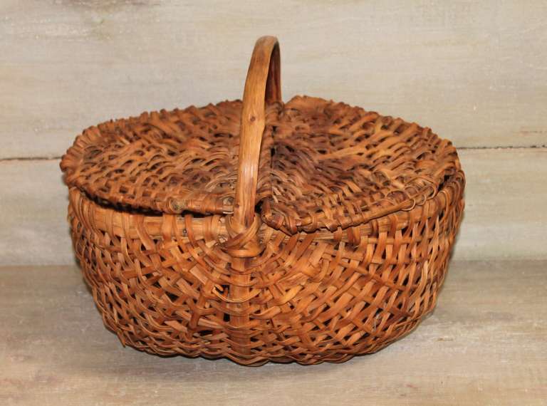 This 19th c. buttocks basket was acquired in Southern Pennsylvania and features hand woven splint oak, a bentwood handle, handmade wire nails with an exceptional natural aged patina.  The lid lies across the basket top showing minor irregularities