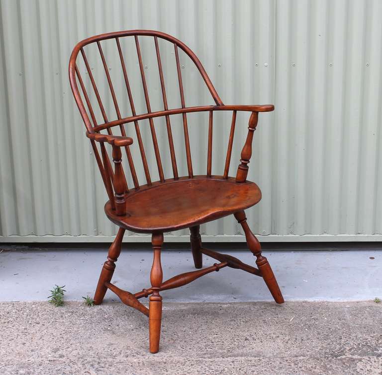 This Knuckle Arm Sack Back Windsor Chair dates to the earlier 1800’s New England and is in exceptional original condition showing a rich and warm patina.  The chair features eleven spindles that tenon through the chair back and arm rails along with