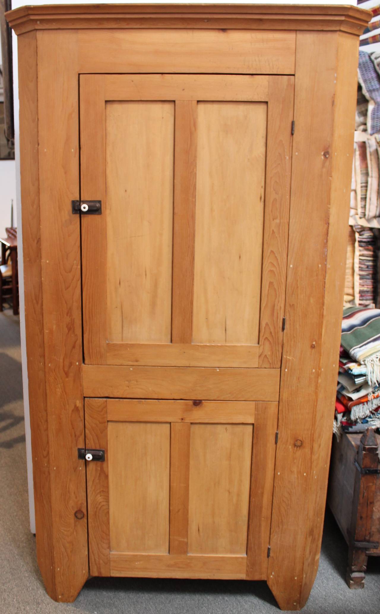 This finely made 19th century Pennsylvania pine two-door corner cupboard is in wonderful as found condition. It has all original hardware and wonderful cut-out feet. The entire cupboard is early square nails and wood peg construction. The backboards