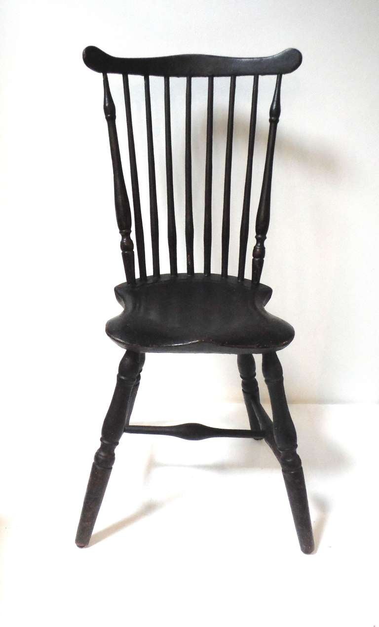 This early 18thc Windsor fiddle back chair retains all original crusty black painted surface with a base undercoating of a red wash.The form is great along with the condition and height of this side chair.It has a very early narrow saddle seat and