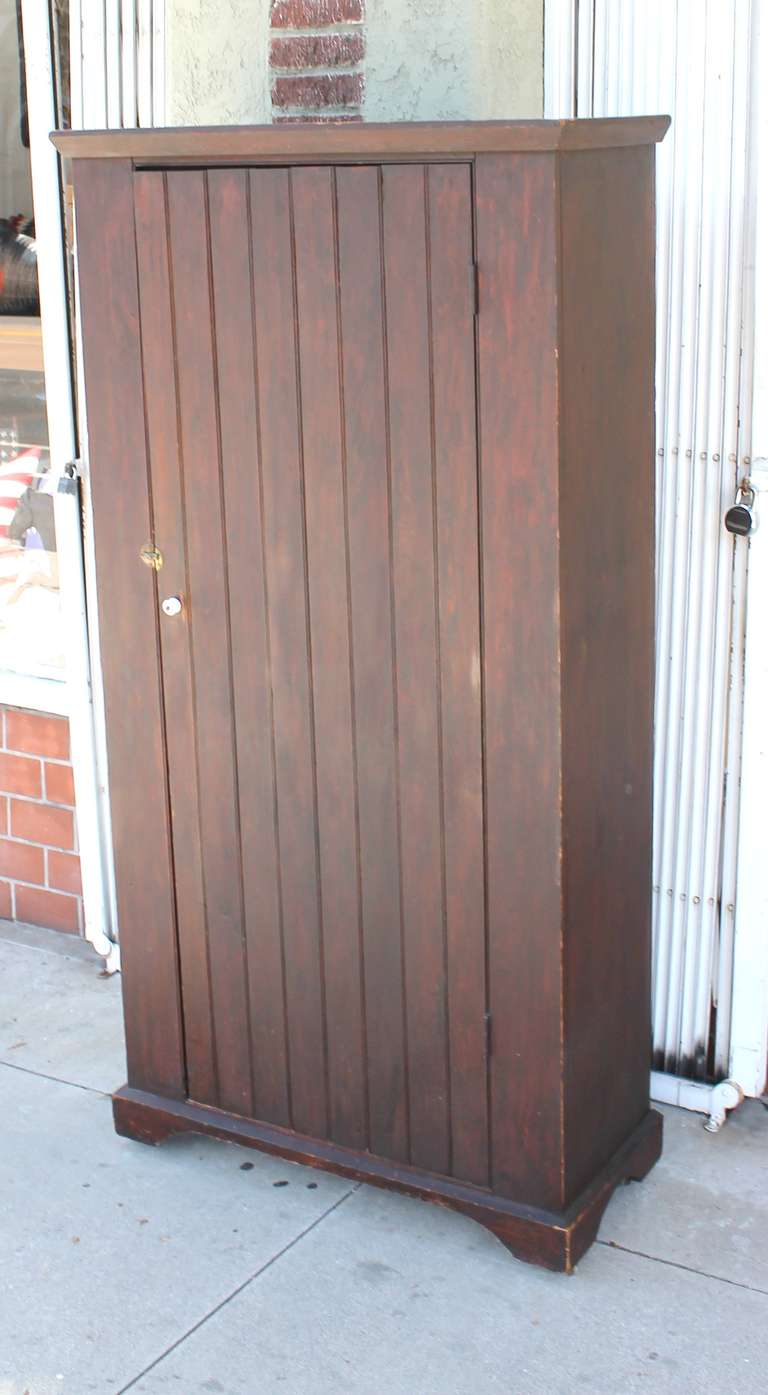 This 19th century Pennsylvania farmhouse wall cupboard shows all original brown paint and hardware with great character and a rich, warm well-used patina.  The interior of the cupboard features four shelves and a skinned pine finish.  The cupboard