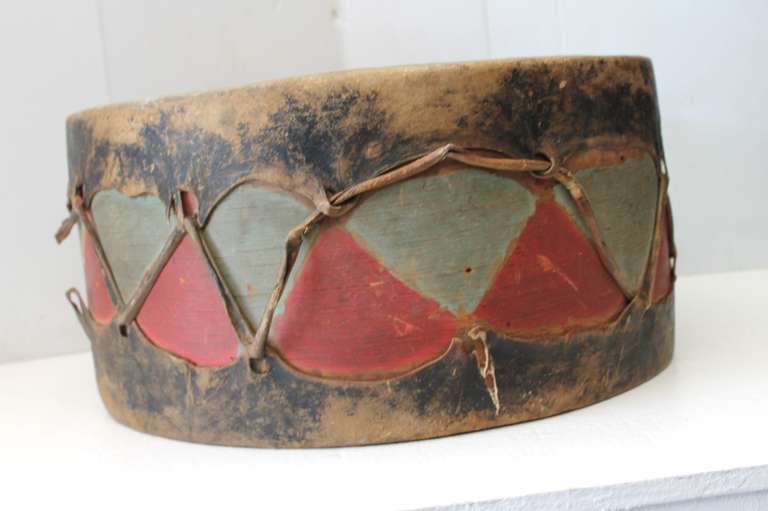 This remarkably well-conserved ceremonial drum from the Pueblo de Cochiti, New Mexico dates to the earlier part of the 20th century and shows all original paint, cottonwood and rawhide. The body of the drum is painted in alternating colors of deep