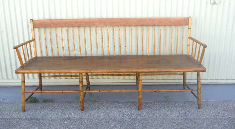 This early 19thc plank seat Windsor bench is in very good condition and is also very comfortable .The fantastic spindles are in bamboo turnings and the arms are all mortised throughout.The form is simple and has a wonderful mellow natural patina.