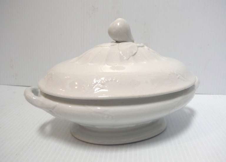 This white ironstone vegetable tureen measures 11 inches long by 7 inches tall. It was made by Jacob Furnival & Co. and bears its JF backstamp. The piece is embossed with lily of the valley sprigs and thumb print designs on the lid with a