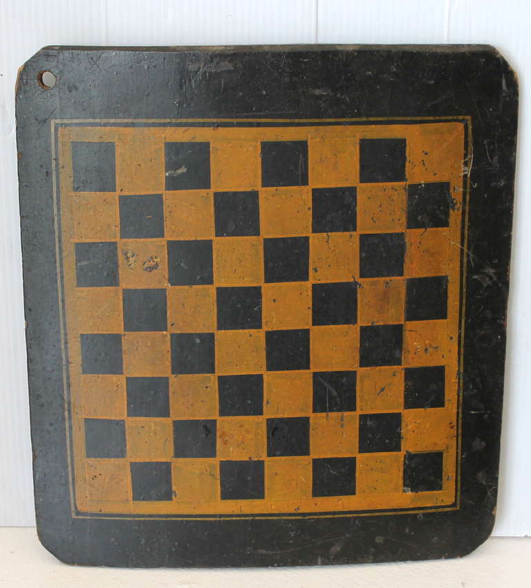 This 19th century “make do” original painted checkers game board shows an outstanding polychromatic original painted wood surface and is constructed from a single wide slightly bowed pine plank. The playing field is painted in chrome yellow against
