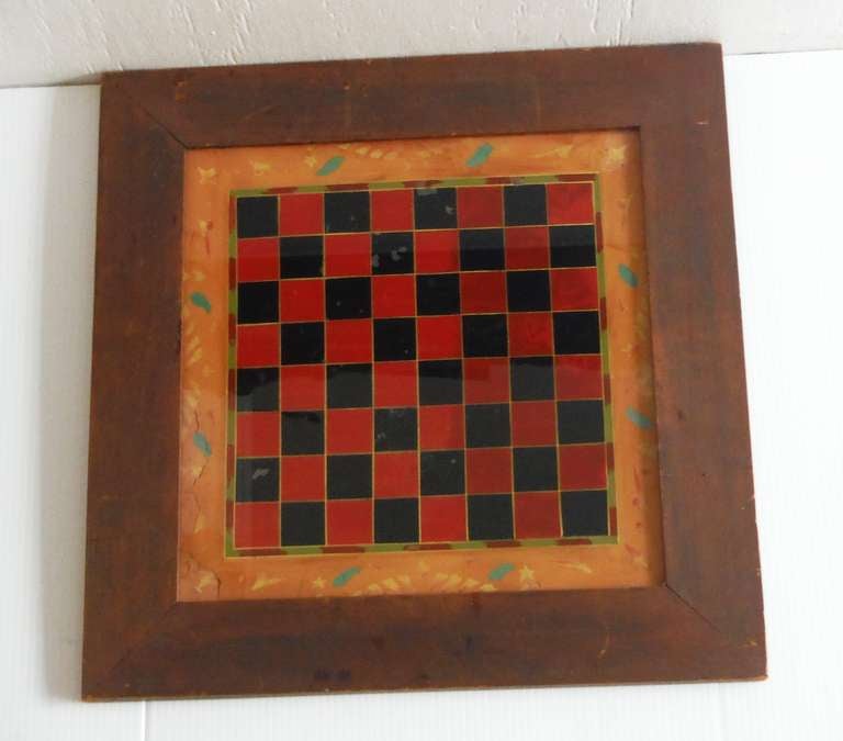 19thc Original reverse  painted game board behind glass in original old surface frame.This red and black checker board is painted on the glass with a very folky decorative wide outer border of stars and moons and what looks like a sun in the middle