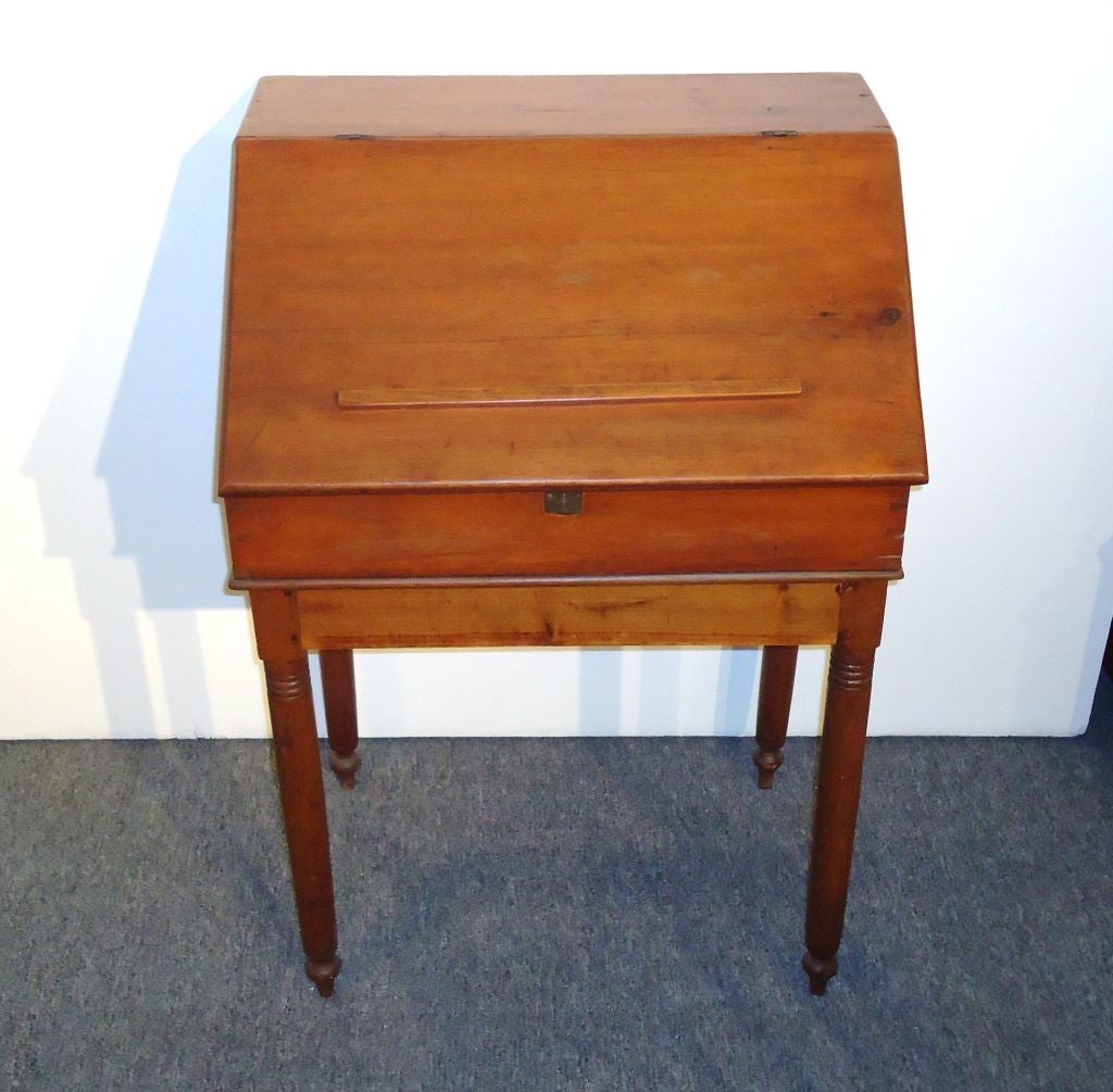 Early 19th century school masters desk from PA in fantastic form and condition. The top part of the desk is dovetailed construction and the base is all wood peg construction and original turned legs. The lap part of the desk has a wood trim attached
