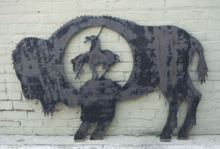 Extra Large sheet iron with the Indian on horseback inside of the monumental buffalo with a wonderful worn patina surface. This alligatored and worn painted trade sign has feet wear it was bolted down on wood or on the ground. This is so cool and