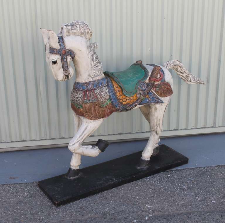 This fantastic folk art Carousel horse is mounted on its original black wood base and is  in great sturdy as found condition. The form is on the order of a Probably from Mexico and has very unique painted colors and carvings. The surface is a later