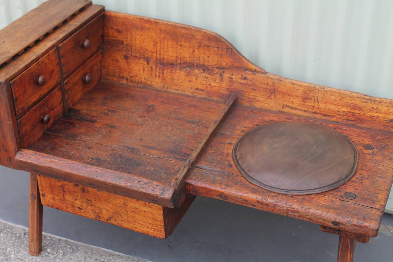 Fantastic and very early 19th century cobblers bench with four original little drawers and one large slide drawer below. The slide drawer below is dovetailed and the little drawers are square nailed construction. This bench has wood pegs and