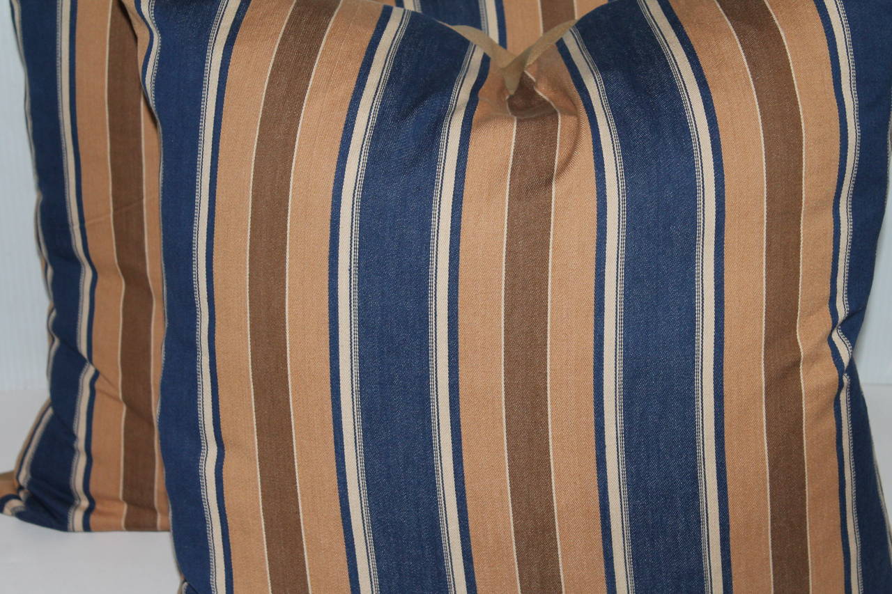 These amazing 19th century brown and blue striped ticking pillows have wonderful brown cotton linen backings. Two pairs in stock. Down and feather fill.