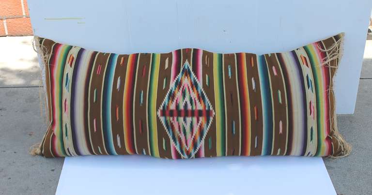 This is a very early serape with the original fringe  bolster pillow.  This is a Mexican-American weaving. The backing is a ecru cotton linen.The insert is down and feather fill.