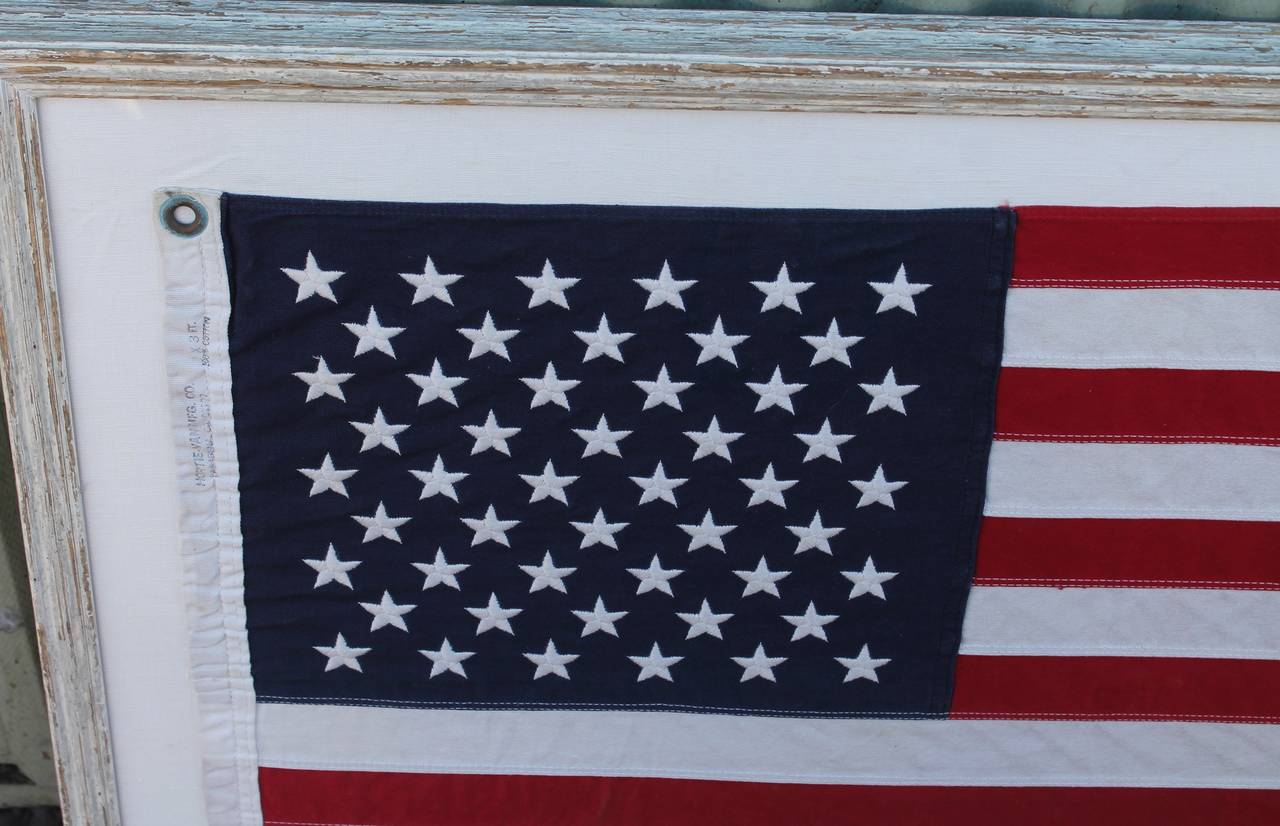 This 50 star American ships flag with custom white distressed frame.
The 50 star American flag was introduced in 1960 with the admittance of Hawaii as the 50th State. This flag is in pristine condition and has minor wear consistent with its age.