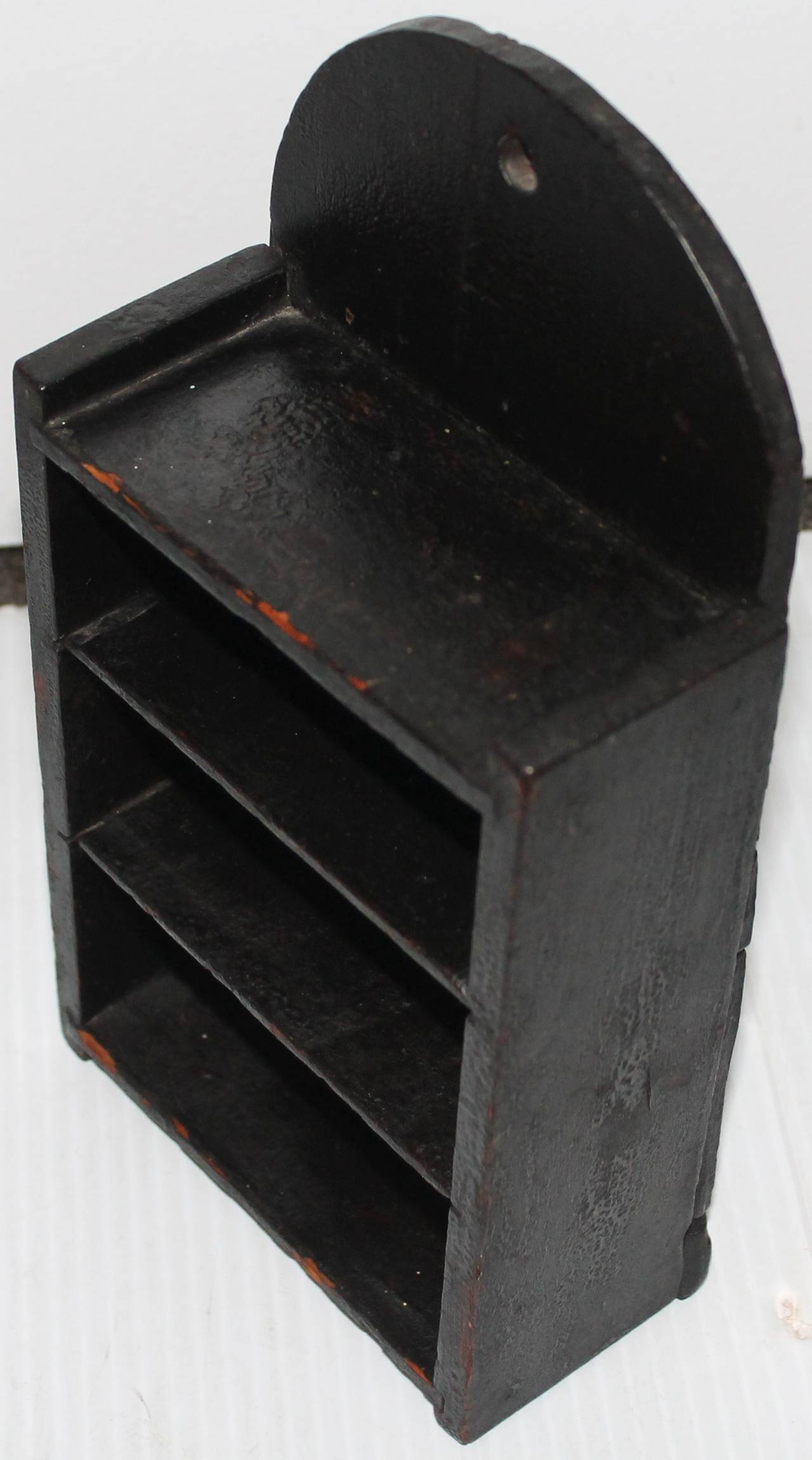 This 19th century black painted wall box shelf was found in Pennsylvania and is in all original black painted surfaces. This alligatored surface shelf was made for tiny smalls or collectables. It also could be used for small Folk Art pieces. The