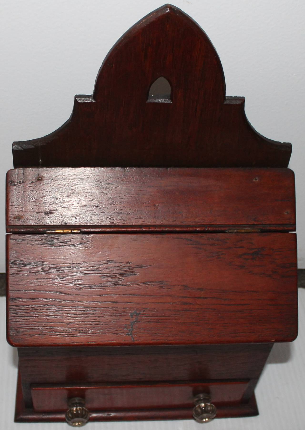 This handmade wall box is made of walnut and is all hand-cut square nail and dovetailed construction. The drawer is dovetailed and retains the original handblown drawer pulls. It was found in Lancaster County, Pennsylvania. The surface is dark and