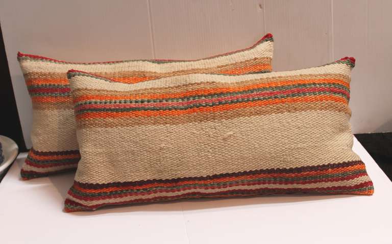 These rustic early saddle blanket pillows are in good condition and have tan cotton linen backing. The inserts are down and feather fill. Sold as a pair.