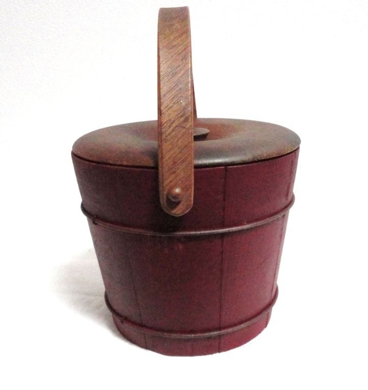 VERY UNUSUAL 19THC DEEP ORIGINAL RED PAINTED BERRY BUCKET WITH METAL BANDS AND MAPLE LID.THE BENTWOOD HANDLE IS MOST UNUSUAL WITH WOOD PEG PINS AT EACH END.THE CONDITION IS VERY GOOD AND IS FROM NEW ENGLAND.