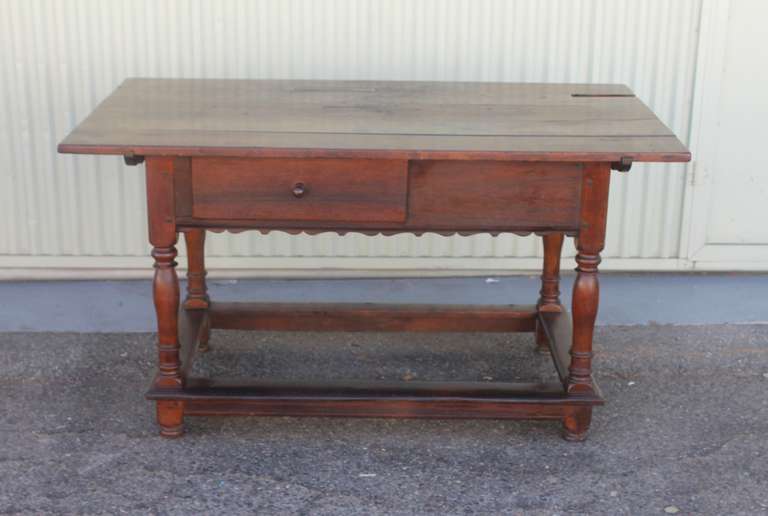 This 18th century Pennsylvania walnut tavern table is handmade nail and wood peg construction. It has wide three board top and pegs for the top of the table. It is most unusual to see a double drawer base. There is a dovetailed drawer in the front