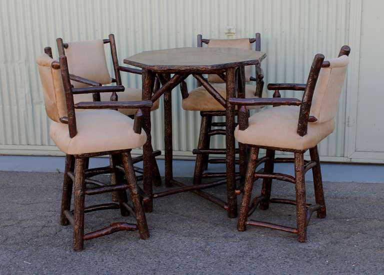 Fantastic matching five piece matching set of Old Hickory bar table and four swivel bar stools. The bar stools are newly covered in a blonde cow hide both seat and backs. The matching table has an octagonal shape and a marquee top. The table is