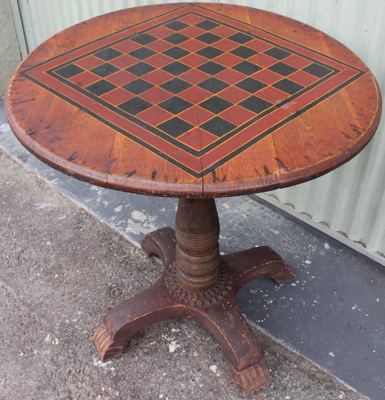 This is such a amazing piece of unusual Folk Art! The tabletop has the original red and black painted checker board like what you see in the old bar or pubs back east. The patina is the best with a crackled surface and worn edges on the diameter.