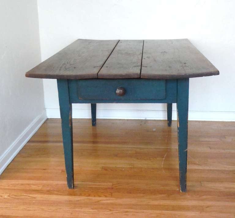 Early original green painted 19th century New England farm table with a drawer in the skirt below the top.  This undisturbed painted surface is a teal blue/ green painted base with the original three board scrub top. This farm table is a ex. Ralph