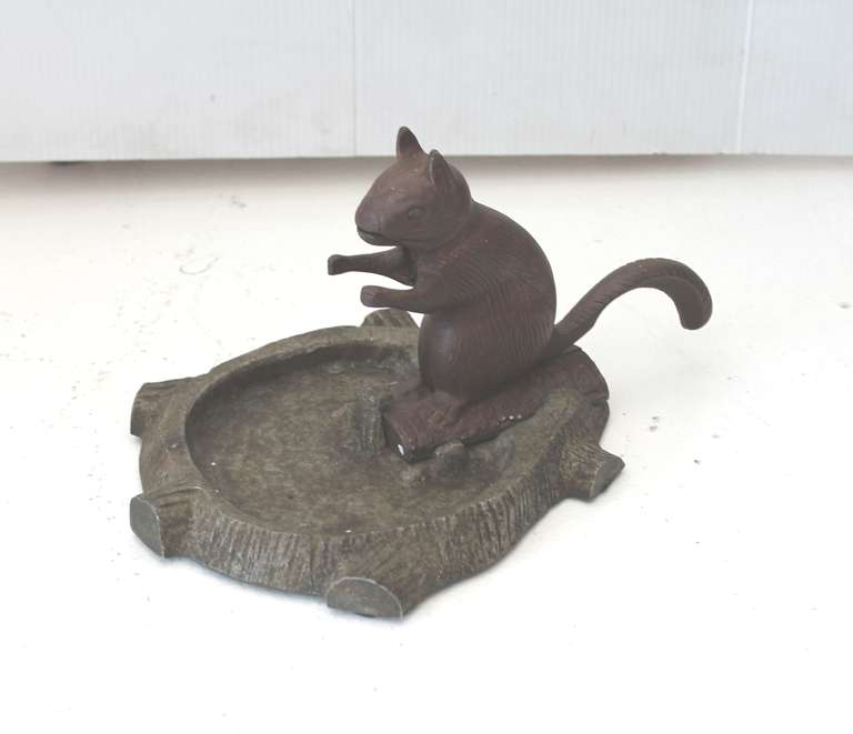 This folky painted squirrel nut cracker is removable from the base. This appears to be iron with a zinc  base. The squirrel nut cracker is painted a chestnut brown and the zinc base is in a antique silver brown. This is most unusual for a nut