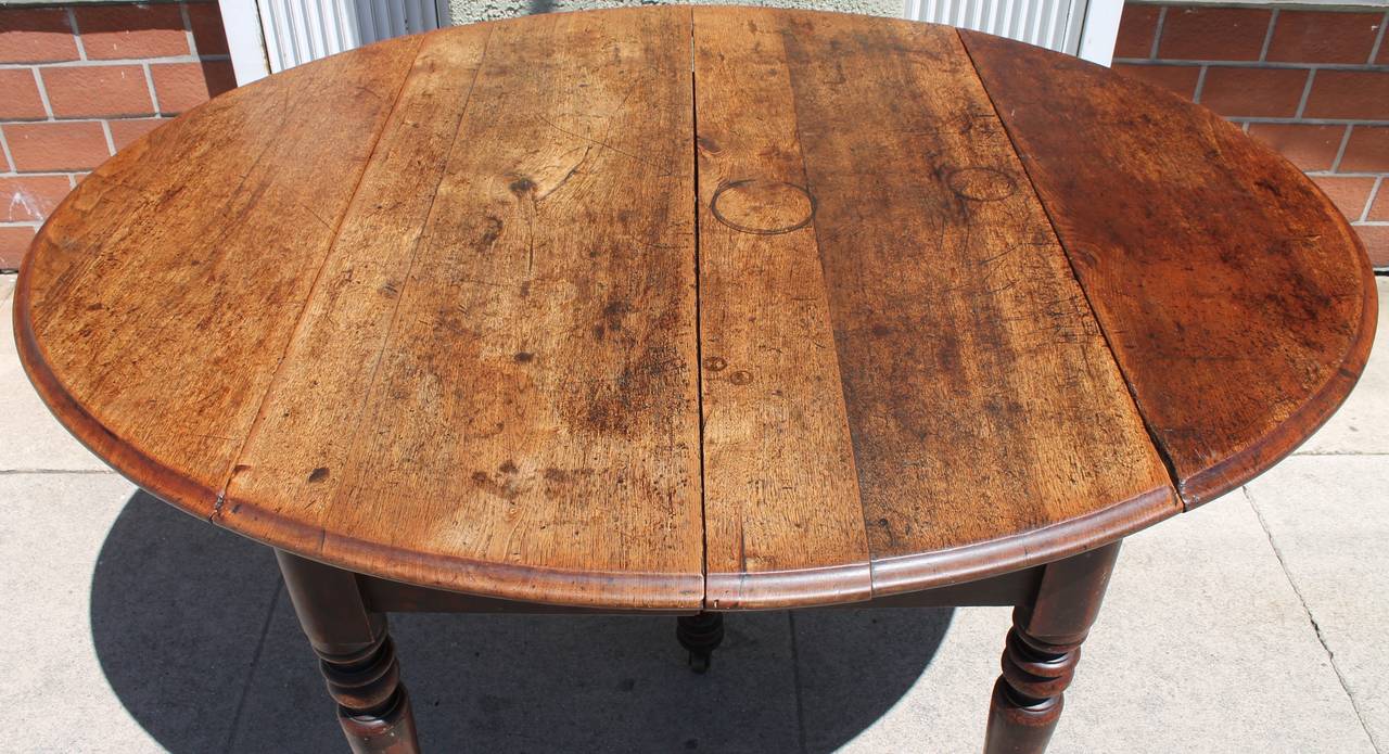 This early and worn walnut drop-leaf table has the best patina ever! It was found in Pennsylvania and works great as a small kitchen table or with the leafs down makes a great sofa table. The legs are all hand-turned with original cast iron casters.