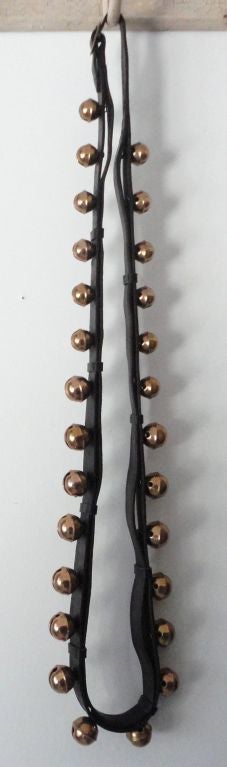 19THC STRING OF BRASS SLEIGH BELLS ON LEATHER STRAP FROM PENNSYLVANIA .THIS GROUP OF 27 BELLS IS ON THE ORIGINAL LEATHER STRAP .THEY ARE IN GREAT CONDITION.