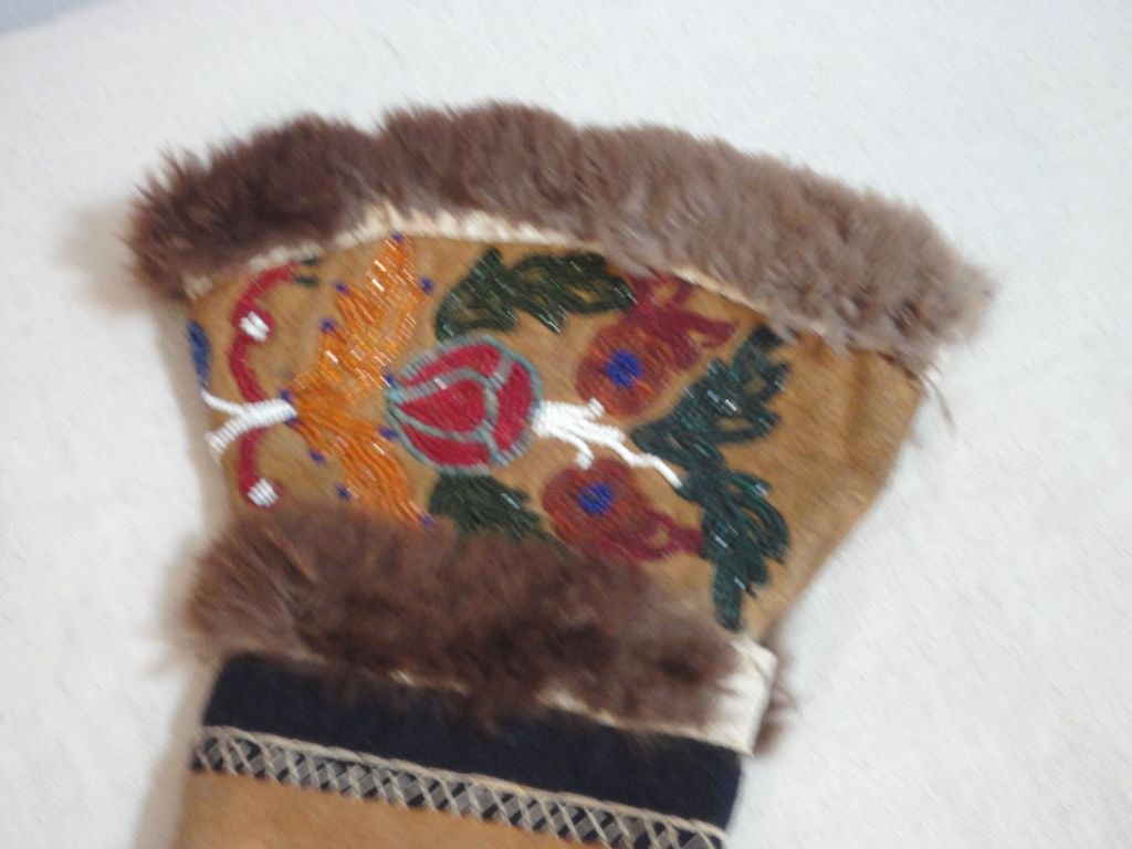WONDERFUL AND VERY WELL MADE INDIAN BEAD WORK BUCKSKIN GLOVES. THE EDGE AND THE MIDDLE OF THE GLOVE IS TRIMMED IN RABBIT FUR AND DETAIL STITCHING .THE LINING OF THESE GLOVES IS A EARLY COTTON INDIAN DESIGN BEACON BLANKET USED TO KEEP WARM.THE
