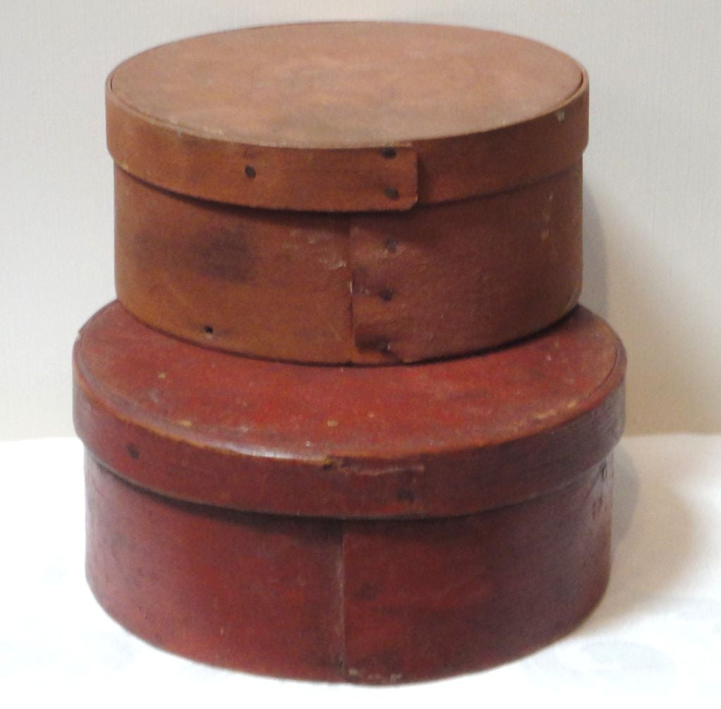 The bottom larger of the two pantry boxes was used for string as they have a hand carved hole in the top of the box.The top is a lighter shade of rust colored paint.Sold as a pair or small stack. Bottom box is 3 high x 6 3/4 deep. Top box is 2 3/4