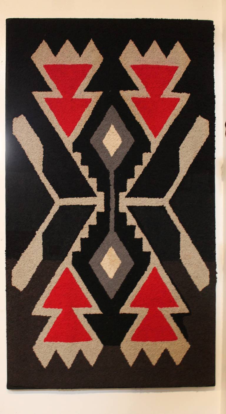 This geometric hand hooked American Indian design rug is in great condition.It is most unusual for a American rug to reflect the typical Indian geometric patterns. This work of art is hand sewn on black cotton linen with a wood stretcher frame.