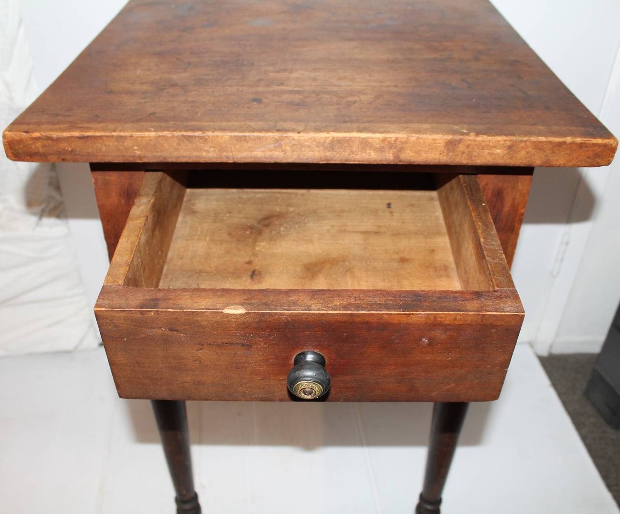 This very early one-drawer nightstand was found in the mid-west in a cabin. The original dry surface tells us its been in a very dry and hot climate with amazing untouched worn surface. The base of the legs retains a original black painted, grungy
