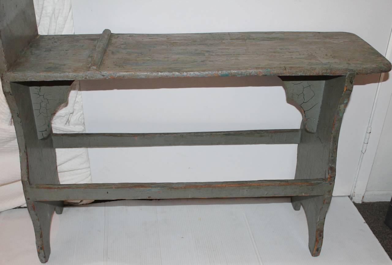 This funky bucket bench has the moat interesting back on one side and wonderful cut-out legs. The construction is square nail and mortised runners. The surface is crackled and worn to be expected. It is very sturdy and strong. It was found at a farm