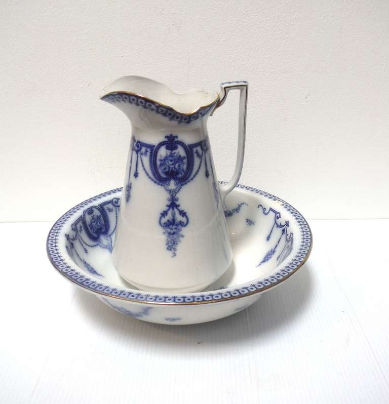 This lovely flow blue pitcher and bowl set is beautifully detailed with decorative contrasting blue and white coloration. This piece dates to the years 1890 -1900 from the Enoch Woods Company and is represented by a crown and 