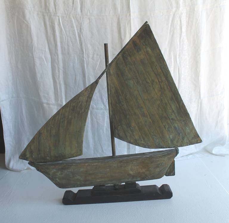 This wonderful handmade 19th century sailboat weather vane is a full body copper vane with amazing worn patina. The sailboat was found in the state of Maine. The condition is very good with a custom made black painted wood base. The condition is