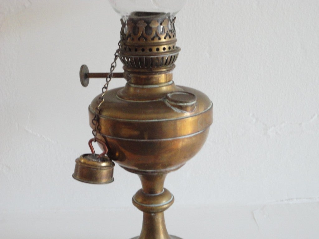 This fantastic early 19thc New England oil lamp has the original glass globe and wonderful brass shield.On the side of this early single light has the snifter on chain for putting out the flame.This is quite a rare form for a brass oil lamp.The