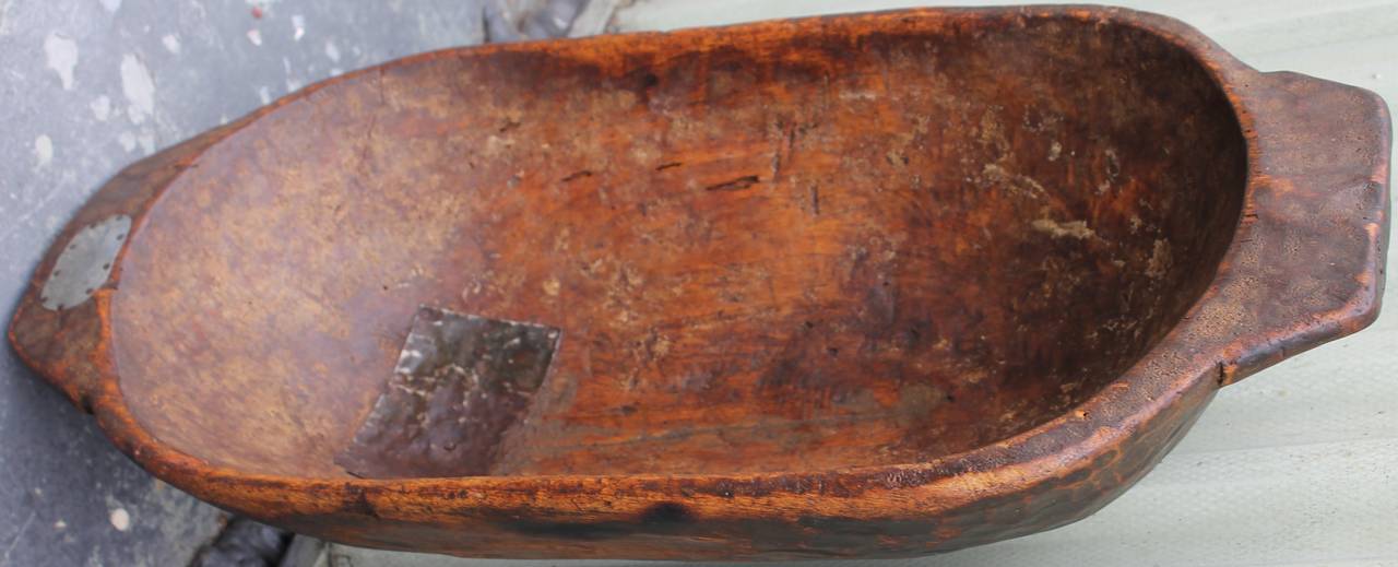 Early hand made and carved dough bowl or trencher. This bowl has wonderful  old tin repairs and wonderful old grungy surface. There is a old early crack that has also been repaired.