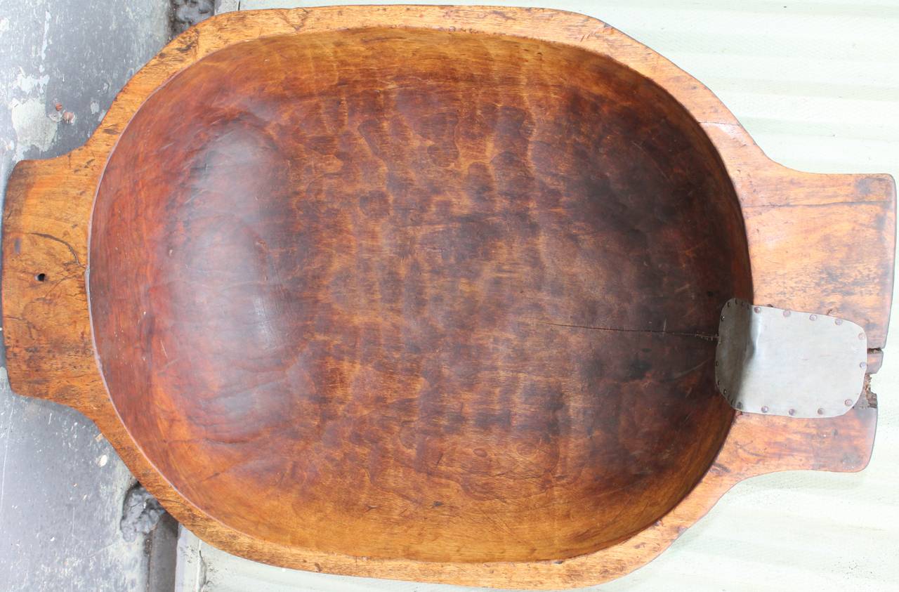 This wonderful worn dough bowl or trencher is in wonderful condition with a beautiful mellow patina. It has a small old tin repair on the right handle and a minor crack that runs through the base of the bowl. Great serving bowl for fruit or outdoor