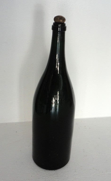 This fantastic early American 19thc dark green oversize wine bottle has the original kick up bottom and early original wood cork.The size is great and it is quite rare to find these early large bottles in such mint condition.This is so cool for