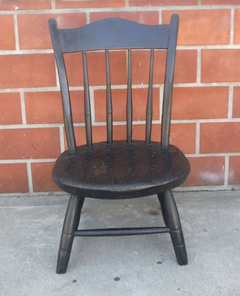 Dies ist ein außergewöhnliches und seltenes Beispiel für einen Daumenrücken-Windsor-Stuhl für Kinder mit Originallackierung und handgedrechselten Spindeln  und einem gewellten Rücken.  Das Stück zeigt sein Alter durch die rot gewaschene Unterwolle