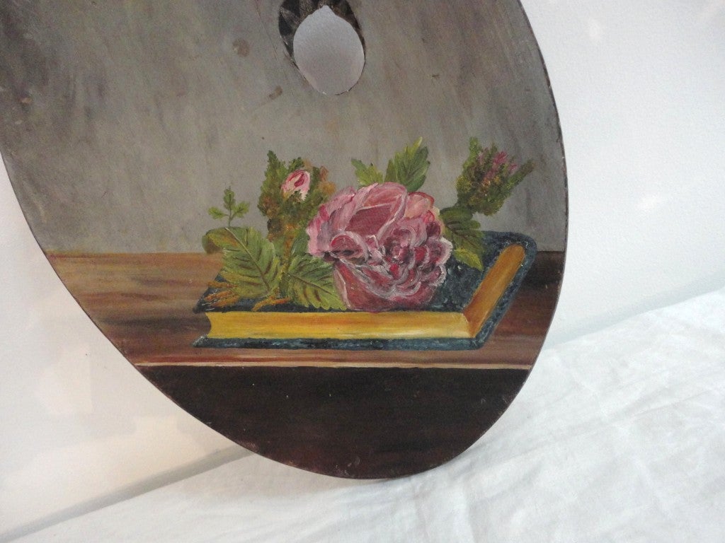 Folky 19thc original painted/decorated paint pallet from New England.This wonderful painted artist board has a rose on a book sitting on a table.The patina is wonderful and the edge has a painted sawtooth pattern all around the board.The condition