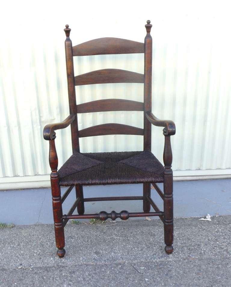 This fine example of early 19thc original untouched surface New England furniture has great form and function .This ladder back chair is bold yet very comfortable with a straw rush hand woven  seat . The surface is all original old stain finish.The