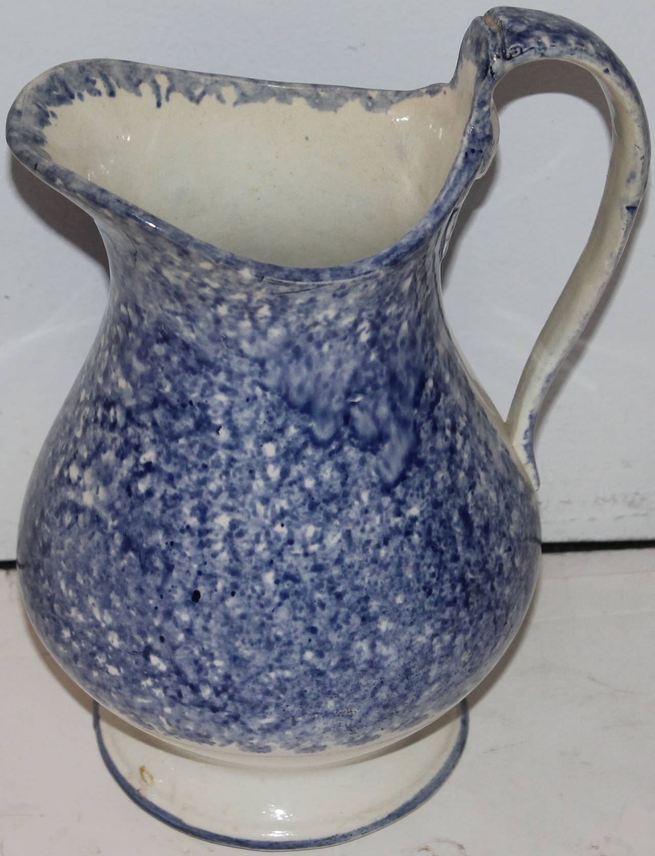 This is quite unusual and very early. The feeling of the pottery is like a soft paste. It is much earlier then most. The color is fantastic. Great addition to any spatter or sponge collection. This is a handmade and painted glazed pitcher.