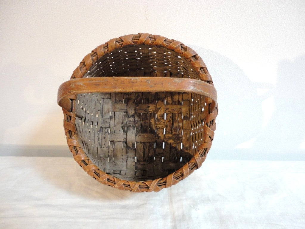 Early 19thc New England painted berry basket in taupe paint with a camel trim band.The condition is very good and sturdy with minor small breaks in the splint on one side.This is always to be expected with a basket of this age.The top rim band is