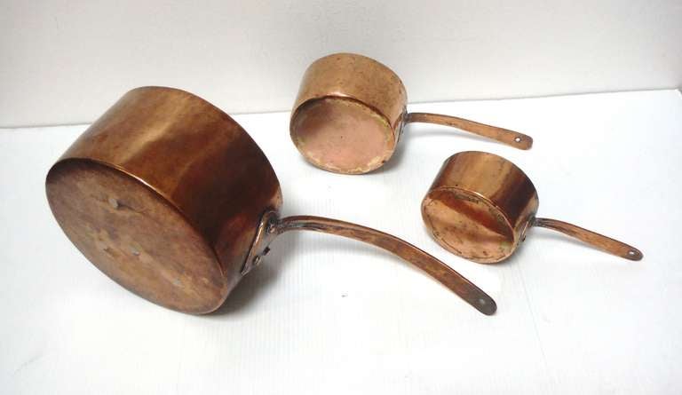 Group of three handmade and forged copper cook pots. This set of three matching pots are polished and all have the original holes for hanging on a wall. The group were found in New England and all are in great condition. Measures: Small one is 3