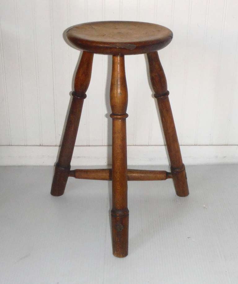 Simple yet elegant, this early 19th century stool shows an outstanding untouched finish. The legs are mortised through the seat standing 20 inches in height. The pie crust border encircles the 10 1/2 inch seat.