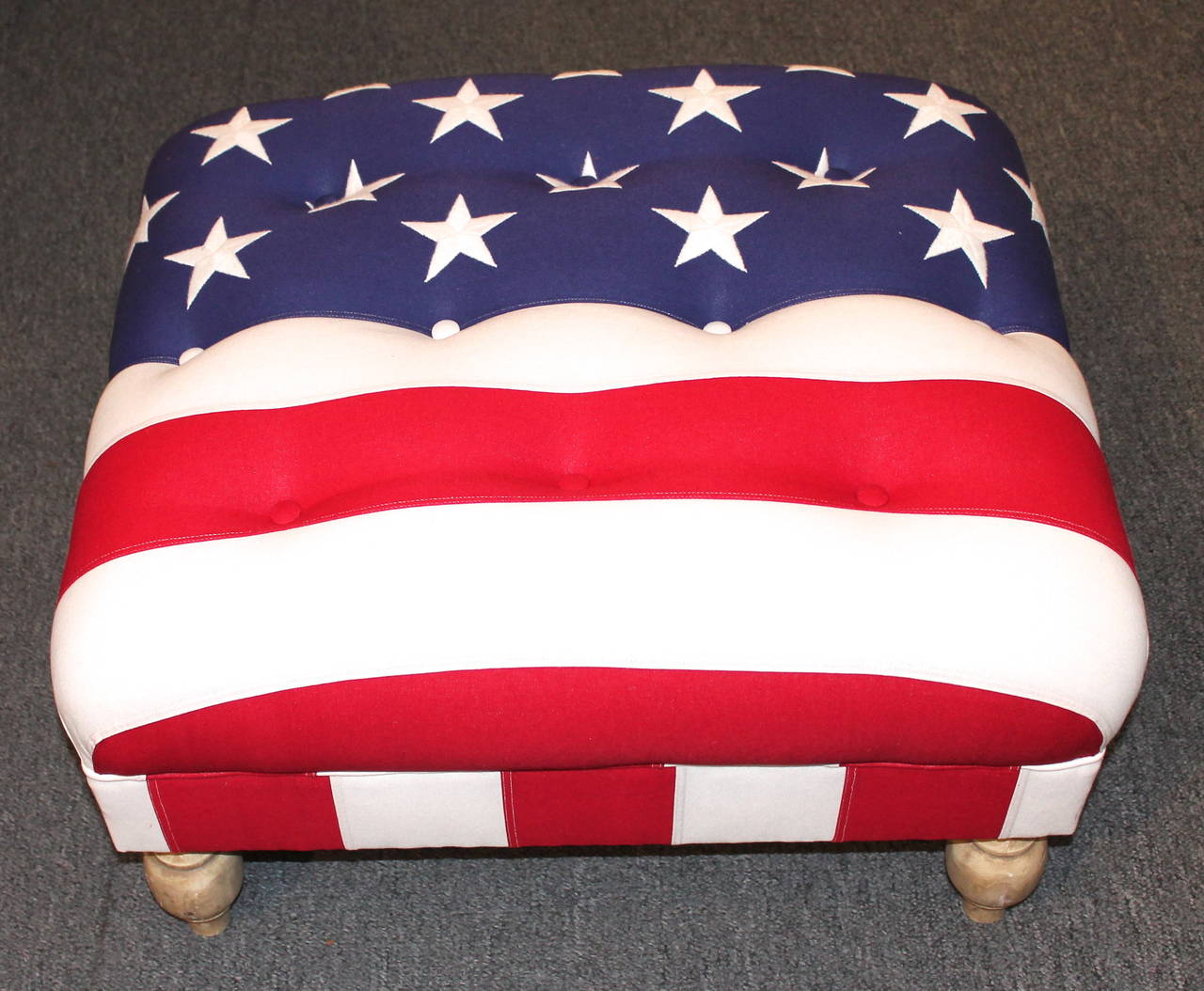 Wonderful and patriotic large ottoman upholstered in a 48 star embroidered wool flag. The spool feet are hand-turned and painted in a distressed cream paint. The condition is very good and sturdy. This could even work as a cocktail table with glass
