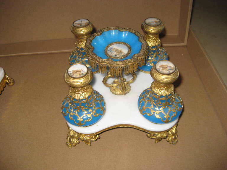 Grand tour monuments in miniature decorate the four lids and center jewel tazza all mounted in gilt bronze and brass on a marble center platform.  The four perfumes and tazza are in blue opaline glass.     The center tazza is a great resting place